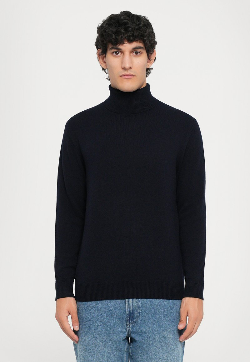 Navyblauwe coltrui met lange mouwen, geribbelde manchetten en zoom, gemaakt van een zacht, glad materiaal. Draag met lichtblauwe jeans.