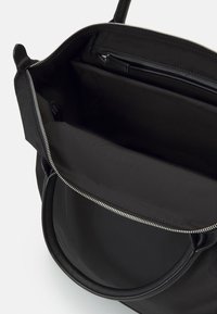 Svart nylon toteväska med dragkedja, med en innerficka och släta läderdetaljer. Strukturerad design och mångsidig form.