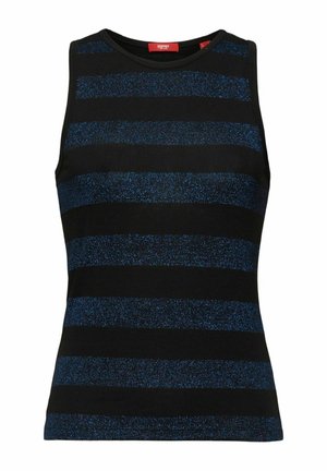 Mujer con una camiseta sin mangas de rayas negras y azules con brillo y un cinturón blanco sujetando la hebilla del cinturón con una mano.
