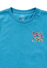 Turkise bomulds T-shirt med rund halsudskæring og en lille, farverig "Volcom"-logo i et legesygt, blandet mønster skrifttype på venstre bryst.