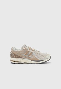 Beige och tan nät löparsko med dämpande sula, snörning och ett märkt "N"-logo på sidan, visad i höger profil mot vit bakgrund.