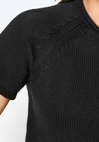 Suéter negro de punto con mangas cortas, un patrón texturizado y un cuello acanalado. El material es suave y con una ligera elasticidad.