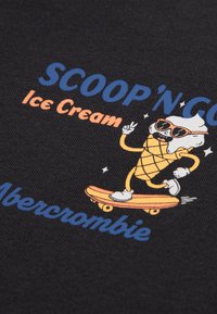 Un tissu noir présente un graphisme d'un personnage de cône de glace en train de patiner avec des lunettes de soleil, accompagné d'un texte bleu et orange, "SCOOP'N GO Ice Cream" et "Abercrombie".