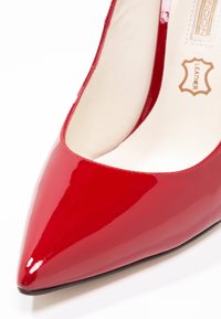 Chaussure femme en cuir rouge brillant à bout pointu, doublure intérieure crème et étiquette en cuir à l'intérieur.