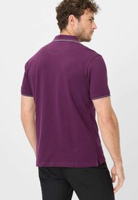 Paarse poloshirt met korte mouwen, voorzien van een contrasterende streep op de kraag en mouwen, gemaakt van een gladde, textuurstof.