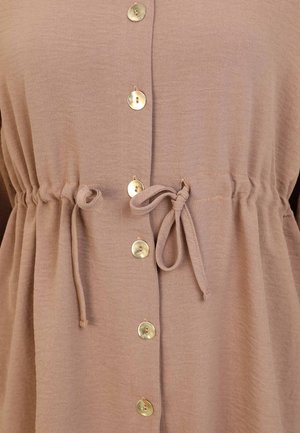 Light brown, textured fabric top with a cinched waist, featuring gold buttons down the front and ties at the waist for adjustable fit.