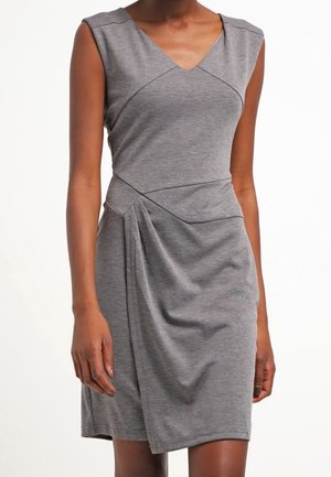 Robe grise sans manches, longueur genou, avec décolleté en V, taille cintrée et détail drapé sur la hanche gauche portée par une personne à la peau de ton moyen-foncé.