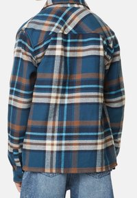 Flannel skjorte med et blåt, brunt og hvidt ternet mønster, med lange ærmer, spidse kraver og knapmanchetter. Blød tekstur.