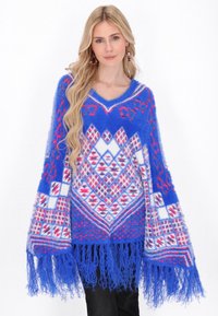 Poncho albastru cu model, cu decolteu în V, având forme de diamante și detalii cu franjuri. Fabricat dintr-un material pufos cu accente roz și alb.
