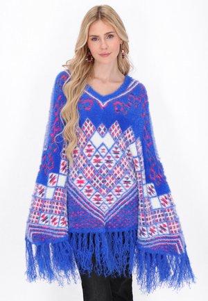 Blauwe poncho met een V-hals, voorzien van diamantvormen en franjes. Gemaakt van een donzig materiaal met roze en witte accenten.
