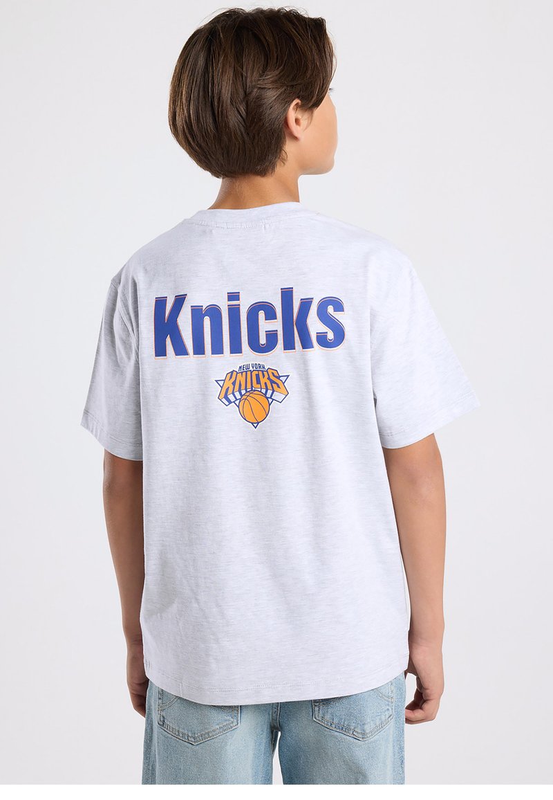 Gray cotton t-shirt featuring "Knicks" in blue letters on the back, with a basketball logo below it. Casual fit, short sleeves, round neckline.