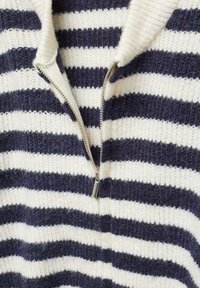 Pull en tricot avec des rayures horizontales bleu marine et blanches, fermeture éclair argentée partiellement ouverte au col côtelé.