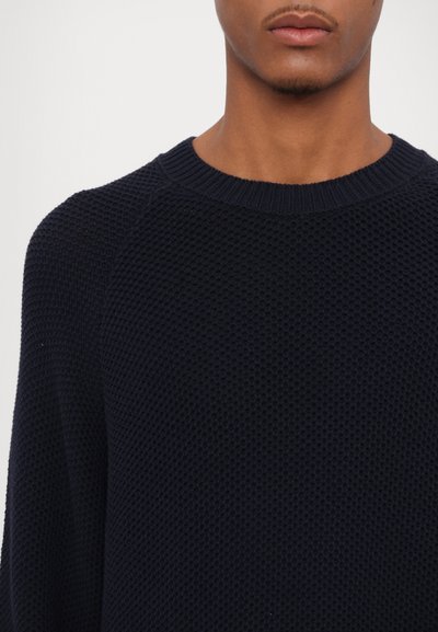 Pull en tricot coton bleu marine foncé, avec un motif texturé, un col rond côtelé et des manches raglan.