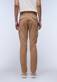 Homokszínű cargo nadrág, könnyű anyagból készült. Slim fit fazon, két nagy oldalzsebbel és két hátsó zsebbel. Sima textúra és minimalista dizájn.