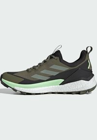 Zapatillas deportivas verdes y negras con un upper texturizado, material de malla, una media suela blanca gruesa y una suela exterior con dibujo multidireccional.