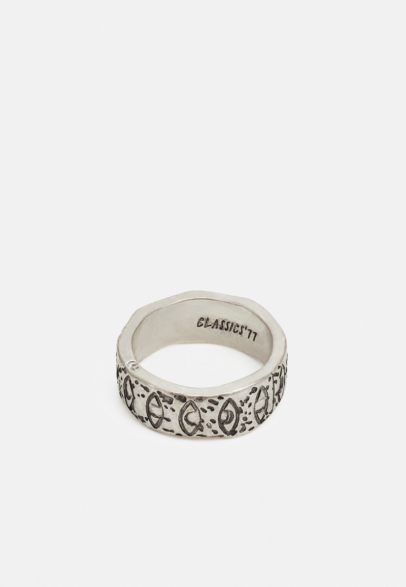 Anel de prata com uma forma hexagonal, apresentando padrões e acentos gravados. No interior, marcado com "CLASSIC '77." Textura suave, acabamento polido.