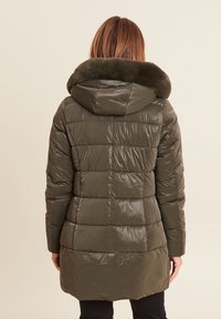 Olijf groene pufferjas met een glanzende afwerking, gearceerd ontwerp en een grote met bont gevoerde capuchon. De achteraanzicht laat een langere zoom zien.