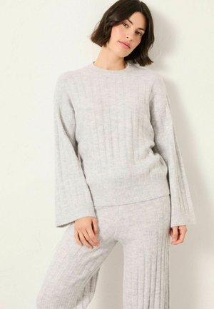Light gray knitted sweater with ribbed texture and long sleeves, paired with matching ribbed pants, displayed against a neutral background.