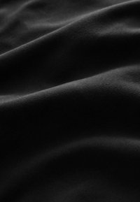 Tissu noir avec une texture douce et lisse, affichant de légères plis et creases. La surface semble mate sans motifs ou accents visibles.