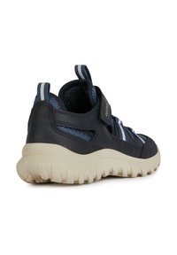 Zapatilla deportiva azul marino con parte superior de cuero y malla, acentos a rayas y una suela de goma beige con textura para mayor agarre.