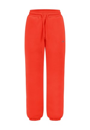 Pantaloni tuta rossi brillanti con vita elasticizzata, cordoncino, polsini elasticizzati e un piccolo logo sulla coscia destra, mostrati su uno sfondo bianco.