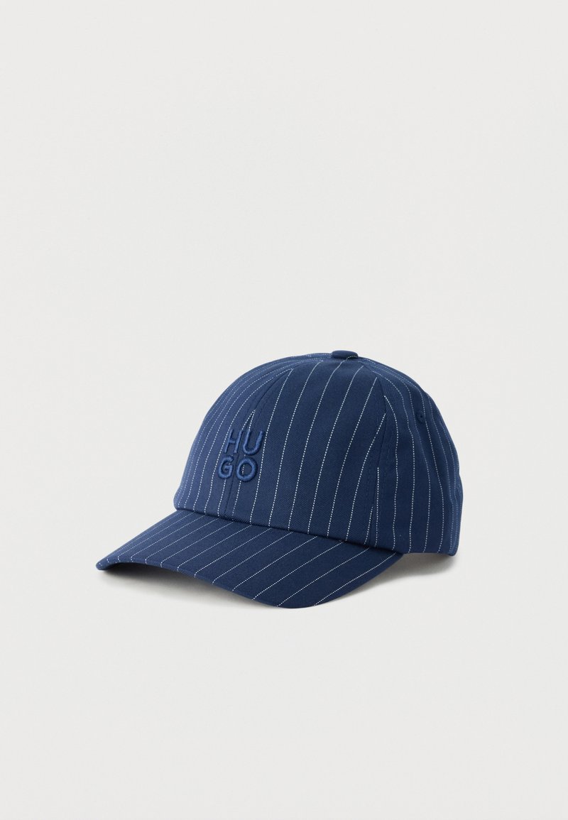 Casquette de baseball bleu marine avec fines rayures blanches et logo "HUGO" embossé à l'avant, présentée sur un fond blanc uni.