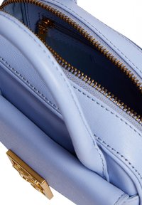 Borsa a tracolla in pelle blu con dettagli in zip dorati, caratterizzata da una forma strutturata e una piccola tasca frontale con un accento in hardware dorato.