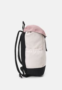 Sac à dos avec un dessus rose, un corps crème et une base noire. Il comprend des sangles ajustables, une poche latérale et une finition en tissu texturé.