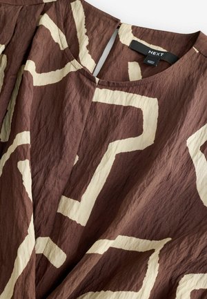 Brązowy top z materiału z beżowym abstrakcyjnym wzorem, z okrągłym dekoltem i pomarszczoną teksturą. Etykieta marki widoczna wewnątrz.