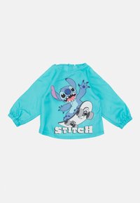 Blå langermet skjorte i glatt stoff med en tegneseriefigur på en skateboard og teksten "STITCH" i fete, hvite bokstaver.