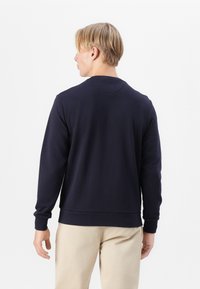 Felpa blu navy con maniche lunghe e colletto rotondo, realizzata in tessuto morbido. Presenta un orlo e polsini ribattuti, con una superficie liscia.