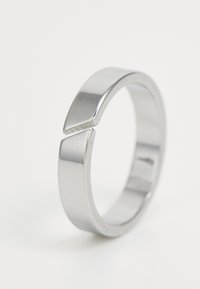 Zilveren ring met een slanke, afgeronde band en twee hoekige accenten die een opening creëren. Hoogglans afwerking met een gladde textuur.