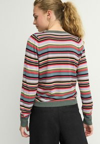 Pull rayé avec des lignes horizontales multicolores en rouge, rose, noir et vert. Manches et ourlet côtelés avec une coupe standard.