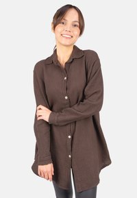Brown, textured button-up shirt with a relaxed fit, long sleeves, and a collar. Features a slightly longer back and small buttons.