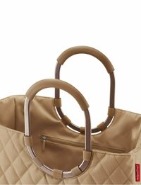 Tan quilted tote bag with rounded metal handles and textured grips. Features an inner zippered pocket. Accented with a red label tag.