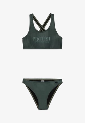 Tamni zeleni badić izrađen od rebraste tkanine. Top ima preklopne naramenice i otisnuti tekst; donji dio ima kontrastnu unutrašnjost.