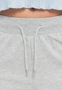 Lichtgrijze joggingbroek met een elastische tailleband, trekkoorddetail en een zachte textuur, geschikt voor vrijetijdsgebruik.