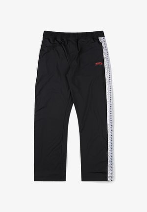 Crne sportske hlače s bijelim bočnim prugama koje imaju mali uzorak ponavljajućeg logotipa i crveni izvezeni tekst na lijevom bedrima.