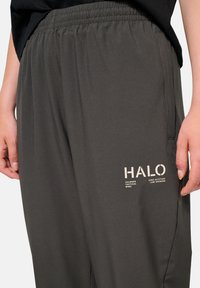 Donkergrijze, lichte broek met een elastische tailleband. Heeft een ribbeltextuur en zijzakken. Een "HALO" logo is op het been gedrukt.