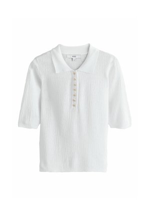 Tricou polo alb cu mâneci scurte din material tricotat texturat și șase nasturi mici aurii în formă de stea pe fenta din față.