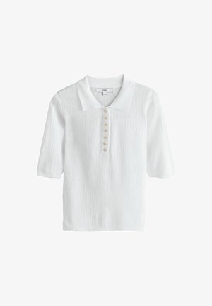 Fehér, rövid ujjú kötött galléros póló texturált anyagból, elöl hat kis aranyszínű csillag alakú gombbal a placket mentén.