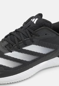 Svart og hvit atletisk sneakers med mesh-overdel, svarte lisser, hvit såle og tre hvite striper på siden.