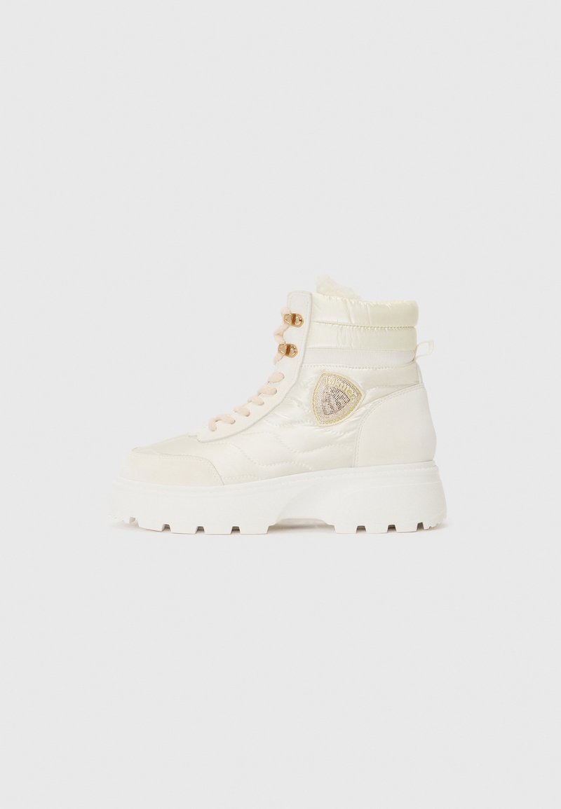 Høye hvite støvler laget av quiltet materiale med polstret krage, med en teksturert logo-patch og en kraftig hvit såle.