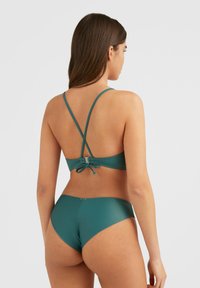 Tyrkysový bikiny set s topom so skríženými popruhmi a nastaviteľným viazaním. Hladká, matná textúra. Spodná časť má vysoký strih pre elegantný siluetu.