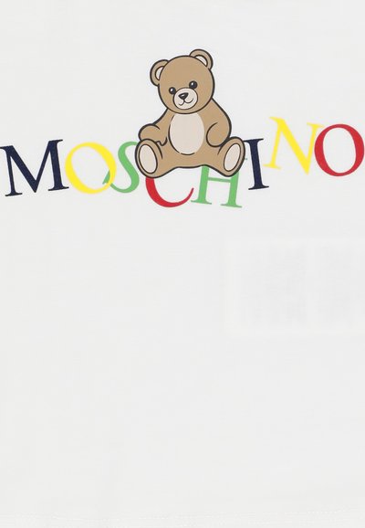 Un orso di peluche marrone è posizionato sopra lettere multicolori che formano la parola MOSCHINO su uno sfondo di tessuto bianco.