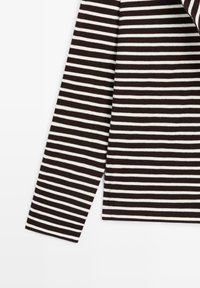 Langærmet beklædningsgenstand med vandrette sorte og hvide striber, der viser nederste del af ærmet og siden af overkroppen på en hvid baggrund.