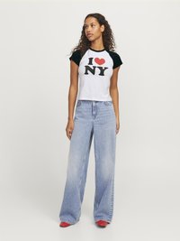 Balts īsās piedurknes tops ar melnum, kurā ir rakstīts "I ❤️ NY" melnā un sarkanā krāsā. Kombinēts ar ziliem platākajiem džinsiem un sarkanām kurpēm.