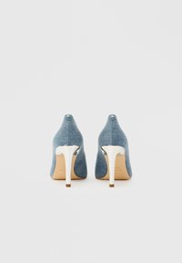 Pantofi cu toc înalt din denim, cu vârf ascuțit și toc stilletto argintiu lucios. Material albastru texturat cu un model țesut subtil.