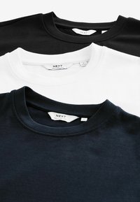 Három rövid ujjú póló fekete, fehér és sötét tengerészkék színben. Pamut anyagból készült, környakú dizájnnal, a "NEXT RELAXED FIT" címkék jól láthatók.