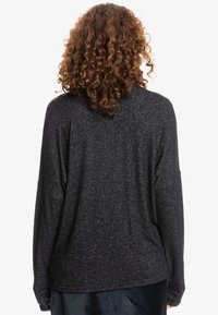 Schwarzes langärmeliges Shirt aus strukturiertem Strickstoff, im entspannten Schnitt und mit heruntergesetzten Schultern, von hinten betrachtet.